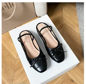 Detailaufnahme schwarzer Ballerinas mit quadratischer Spitze, Schleife und Riemen