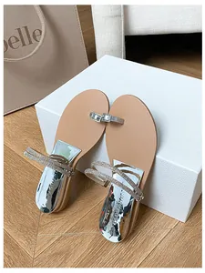 Detail view of rhinestone buckle and metallic silver wedge heel on stylish summer sandals