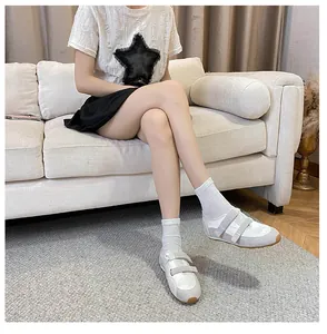 Dettaglio di ballerine bianche e grigie con doppio velcro indossate con calzini