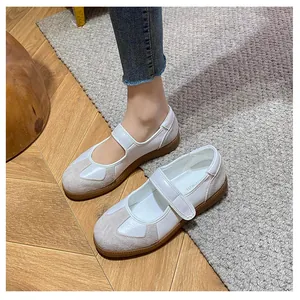 Dettaglio scarpe Mary Jane in pelle bianca e camoscio grigio su sfondo di tappeto
