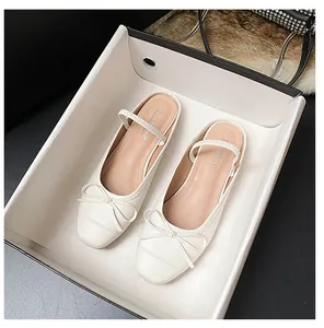 Detail von cremefarbenen Leder-Ballerinas mit Schleife und Riemen in feiner Verpackung