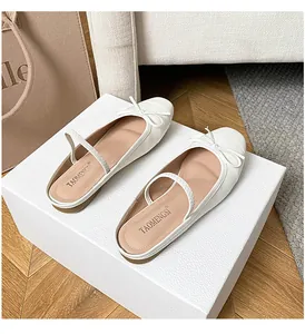 Elegante weiße Ballerinas mit eckiger Spitze und Schleife auf einer Geschenkbox