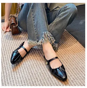 Detailed top view of black Mary Jane flats featuring pleated toe and gold buckle detail