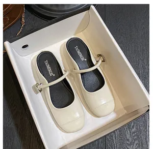 Detail view of cream Mary Jane clogs with buckle strap in a branded packaging box