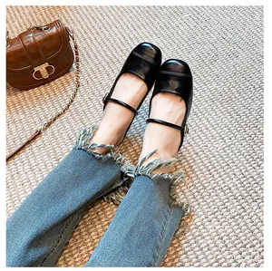 Top view of black Mary Jane flat shoes with buckle strap and round toe on beige rug