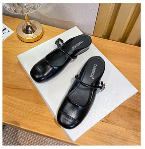 Top view of black Mary Jane mules featuring a buckled strap and matte finish on white board