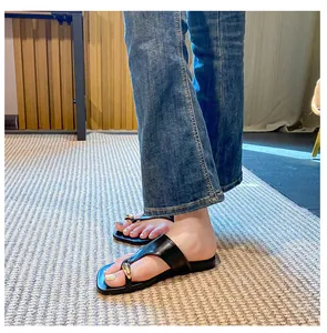 Detail of black thong sandals with metallic gold sphere accent on model feet
