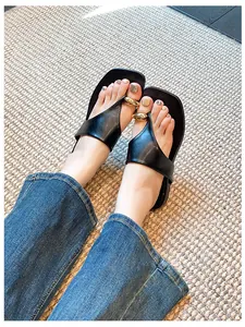 Close-up of black square-toe thong sandals with elegant gold metal bead detailing