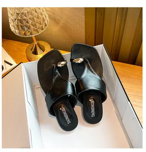 Detailed close-up of black square-toe flip flops with elegant gold teardrop buckle
