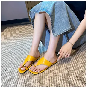 Detail of yellow flat toe-loop sandal with a large gold spherical metal buckle ornament