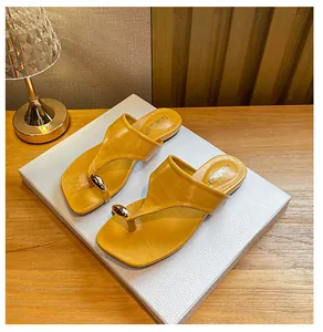 Macro view of square toe flip-flops featuring yellow leather and golden metal drop detail