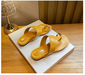 Detailed macro view of mustard yellow leather flip-flops with gold ball metal ornaments