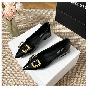 Détail de chaussures plates pointues en cuir verni noir avec grande boucle en métal doré