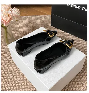 Gros plan de chaussures noires pointues en cuir avec boucle dorée sur boîte blanche