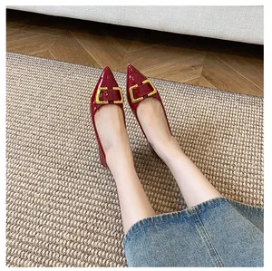 Gros plan sur des ballerines rouges pointues en cuir verni avec boucle dorée