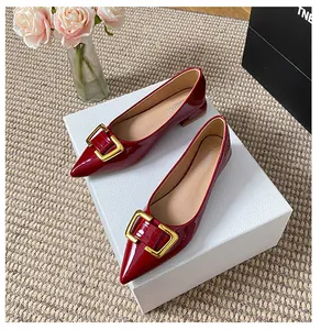 Détail de ballerines pointues rouge vernis avec boucle dorée carrée sur coffret cadeau