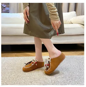 Nahaufnahme brauner Wildleder-Mules für Damen mit Boho-Quasten und weißen Handnähten