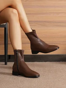 Detailed view of dark brown leather ankle boots with a sleek side zipper closure