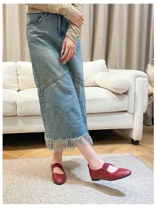 Close-up of dark red leather Mary Jane flats paired with a light blue denim midi skirt