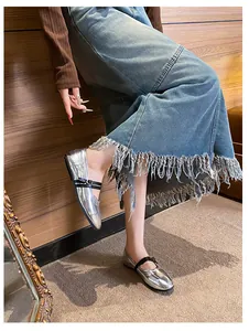 Close-up of metallic silver Mary Jane flats with contrasting black straps on a denim outfit