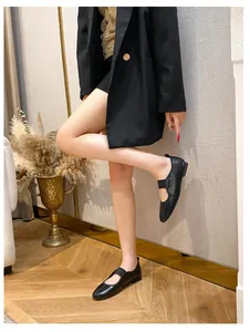 Close-up of black leather Mary Jane flat shoes with elastic strap on wooden floor