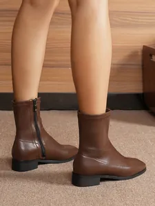 Close-up of brown slim-fit ankle boots featuring side zipper and low block heel