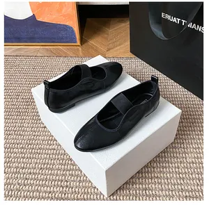 Detailed top view of black leather Mary Jane flats with elastic strap on textured packaging