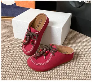 Detail der fuchsiafarbenen Leder-Mules mit gewebtem Seilriemen und Perlen auf weichem Fußbett