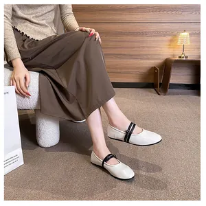Chic beige round-toe Mary Jane flats with double black straps on model in cozy setting