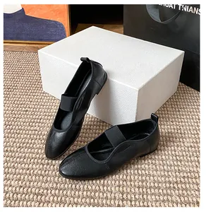 Close-up of black leather Mary Jane flat shoes with elastic straps on woven mat