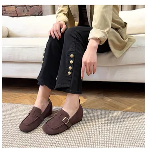 Close-up of deep brown suede loafers featuring 5cm hidden wedge heel and metal buckle details