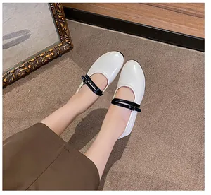 On-foot view of white round-toe Mary Jane flats with black double straps and glossy finish