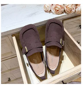 Detailed top view of dark brown suede loafers with metal buckle in a vintage setting