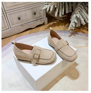 Close-up of beige suede platform loafers with square toe and metal buckle detail