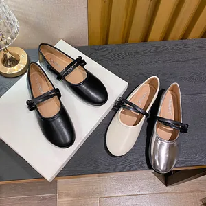 Flat Mary Jane shoes in black, cream, and silver with double buckle straps on a display