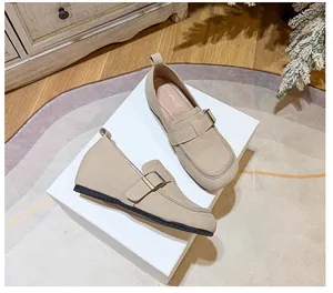 Detail view of beige suede platform loafer shoes with stylish metal buckle on white box