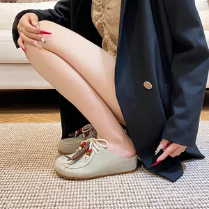 Schicke beigefarbene Leder-Mules im Birkenstock-Stil mit Boho-Webseil und Quasten-Detail