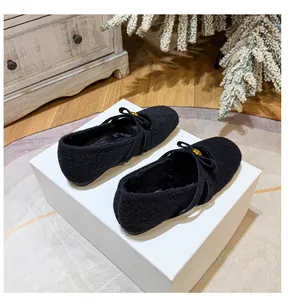 Détail de ballerines Mary Jane noires en peluche avec nœud papillon et boucle dorée