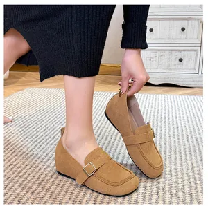 Detail of tan suede loafers featuring a decorative strap and golden metal buckle
