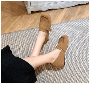 Detailed close-up of brown suede loafers with stylish golden metal buckles on wooden floor