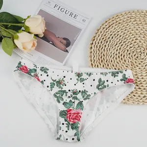 Detail of floral lace panties with red rose prints and black polka dots on white fabric