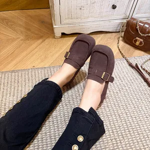 Dark brown suede loafers with metal buckle on wooden floor and vintage background