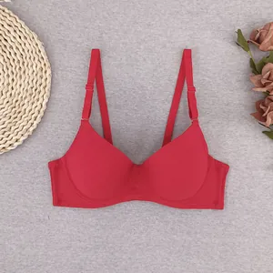 Detailed flat lay of a red lace-free seamless bra with adjustable straps on neutral decor