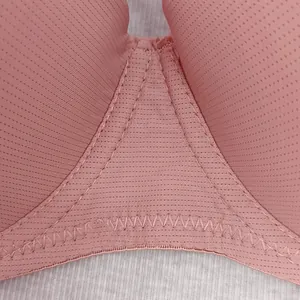 Macro detail of breathable pink lace mesh fabric and reinforced Z-stitch seams on bra