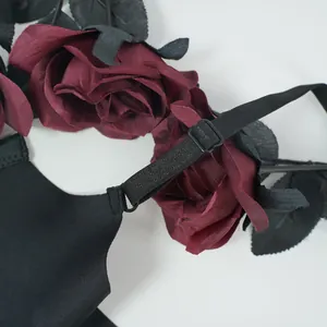 Detail of adjustable black straps and dark red decorative roses on lace bra