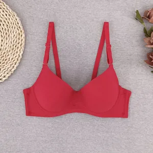 Bright red seamless push-up bra with adjustable straps on a soft textured background