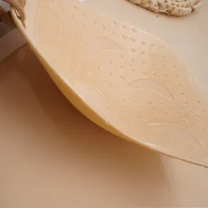 Close-up of beige adhesive bra with breathable crescent cutouts and massage dots