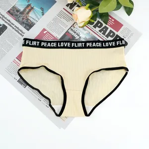 Detail of light beige ribbed panties featuring a black elastic waistband with white lettering
