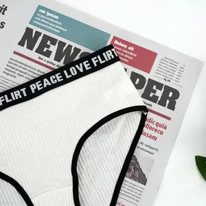 Detail of white ribbed cotton underwear with elastic waistband featuring flirt letters