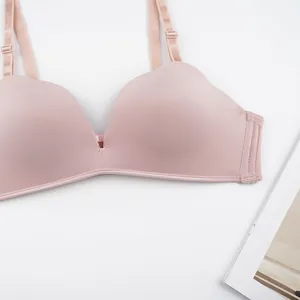 Flat lay of seamless wire-free bra in pale pink with adjustable straps on white background